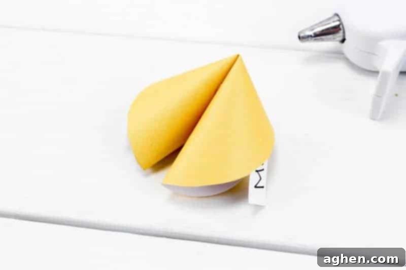 Folding the paper fortune cookie back together after applying glue.