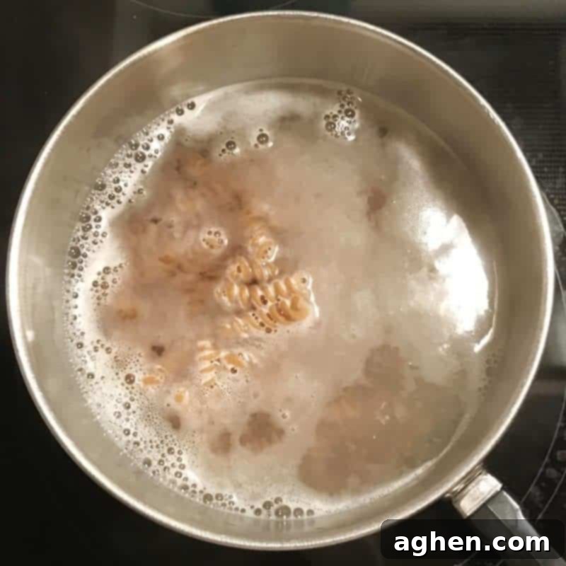 Ingredients for the tuna pasta casserole mixed in a large bowl, showing pasta, tuna, peas, and creamy sauce before being transferred to a baking dish.