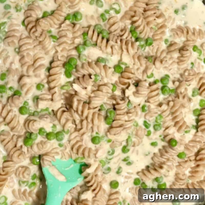 The tuna pasta casserole mixture being spread evenly into a 9x13 inch baking dish before baking.