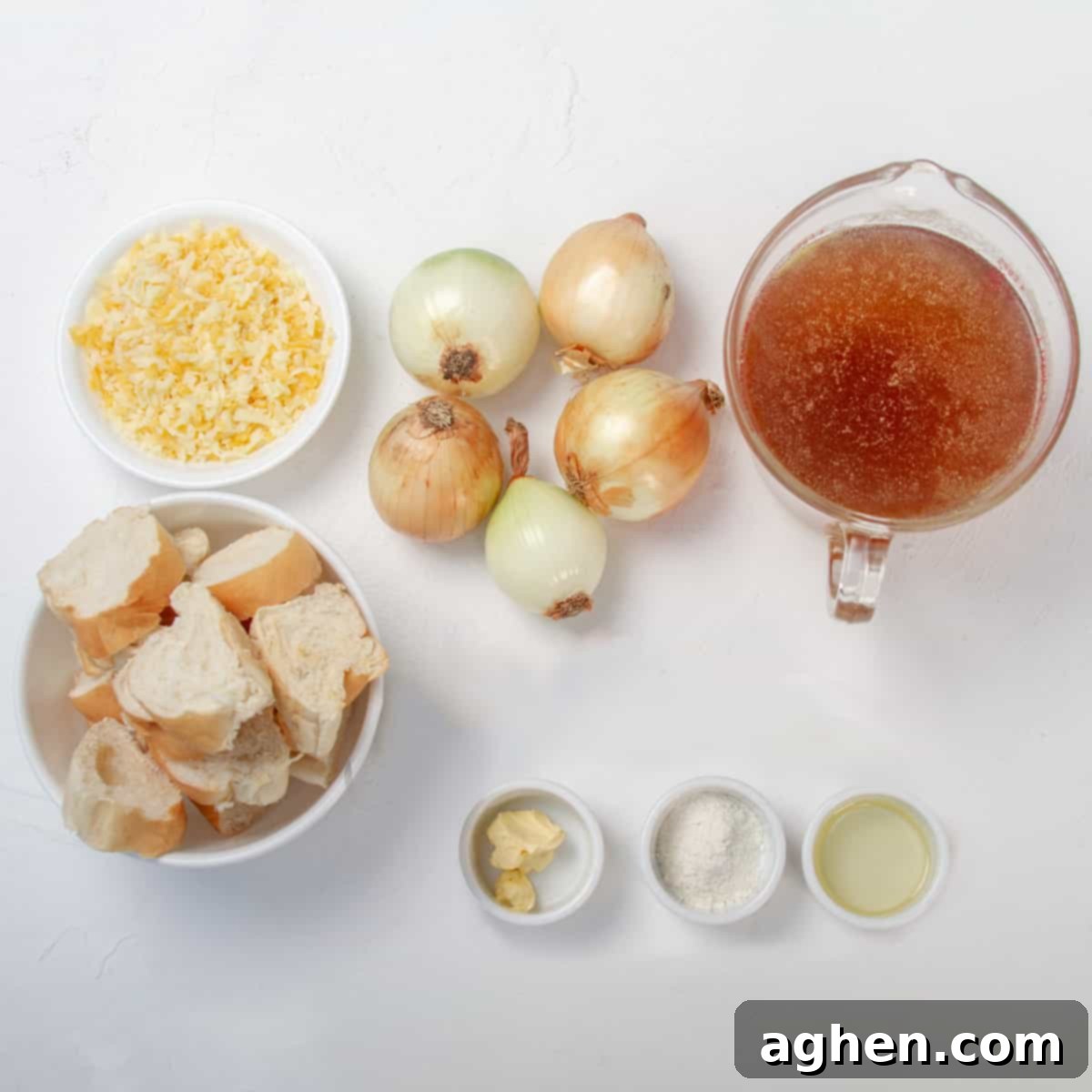 Savory WW Friendly French Onion Soup 3 Ingredients on a table, including a measuring cup of beef broth, 5 white onions, a dish of light butter, a teaspoon of olive oil, a teaspoon cornstarch, 8 slices of artisanal bread, ½ cup shredded mozzarella cheese, and ¼ cup shredded Emmental cheese.