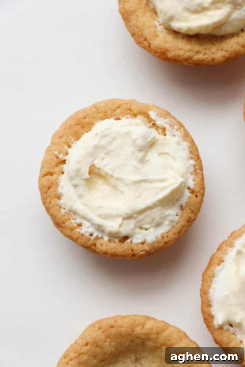 Spoonfuls of creamy banana pudding filling being added to baked sugar cookie cups, ready for their final toppings.