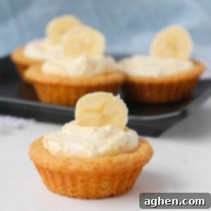 A close-up of a finished Banana Cream Cookie Cup, featuring a golden cookie base, creamy pudding, and a fresh banana slice.