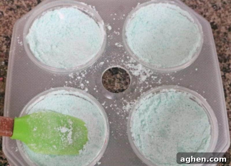 Step 5: The bath bomb mixture is firmly pressed into one half of a mold using a silicone spatula, followed by a light spray of water to ensure a compact and solid formation.
