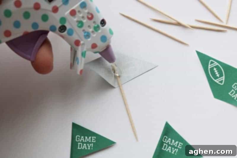 Image demonstrating how to fold and hot glue a toothpick topper flag onto a toothpick.