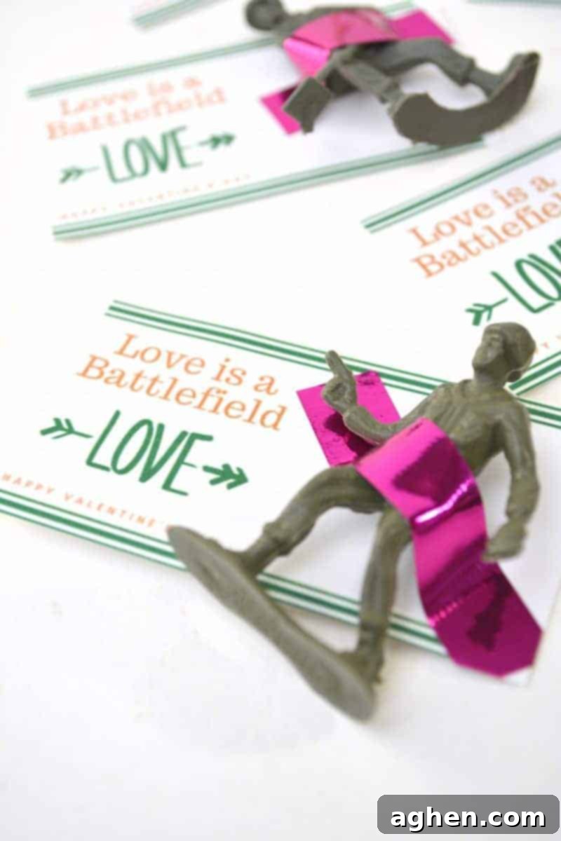 Sweethearts Skirmish Free Kids Valentine Printable 2 Completed DIY Toy Soldier Valentine with a small plastic army man taped to a card that says 'Love is a Battlefield' and 'Happy Valentine's Day', an ideal free printable for kids.