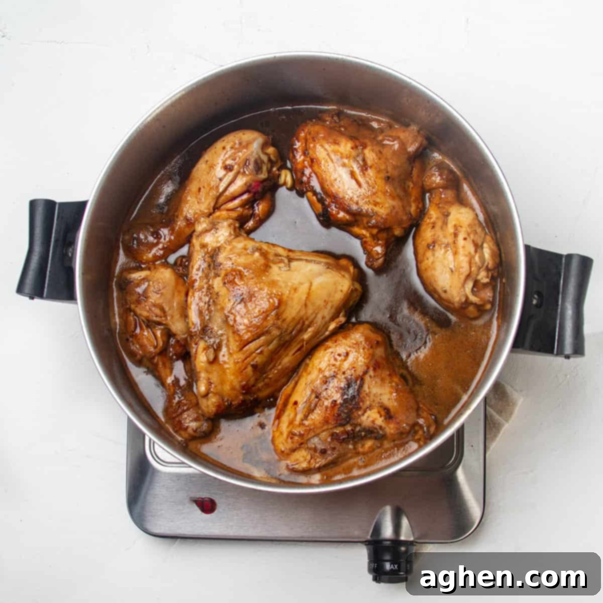 Chicken simmering in shoyu sauce in a hot pan, creating a rich glaze.