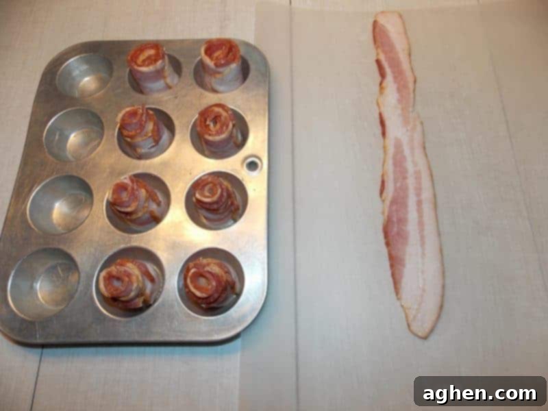 Tightly rolled bacon strips placed in a mini muffin tin, ready for the candied coating and baking.