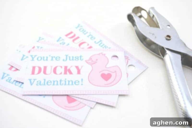 A hand punching a hole in the corner of a 'You're Just Ducky' printable Valentine card.