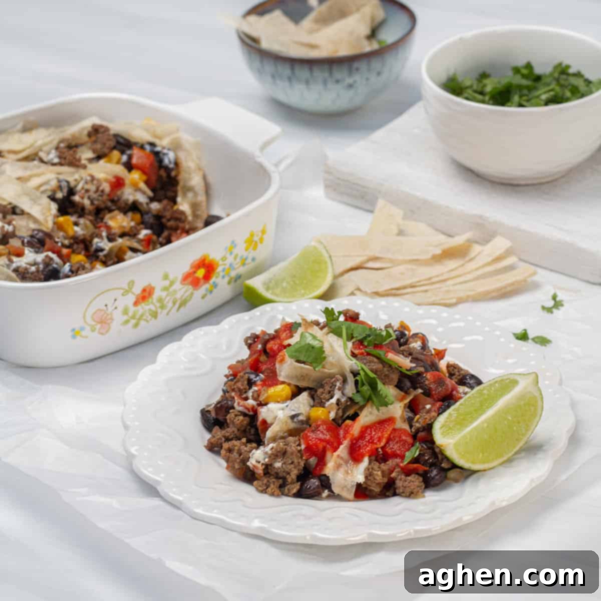 Simple Taco Casserole: Your Taco Night Game Changer 2 Cheesy ground beef taco casserole on a plate, garnished with a lemon wedge and fresh herbs.