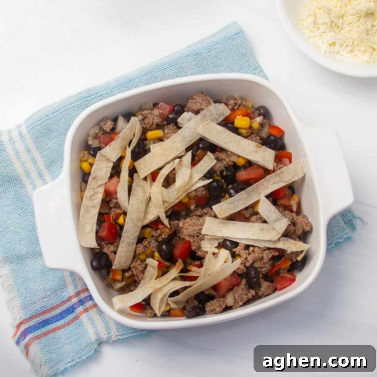 Simple Taco Casserole: Your Taco Night Game Changer 7 Ground beef and veggie mixture topped with tortilla strips in a baking dish.