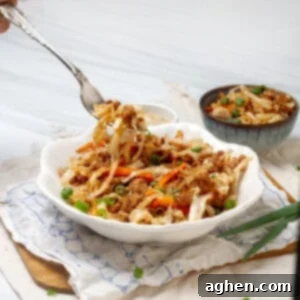 A delicious and healthy egg roll in a bowl dish served in a clean white plate, garnished with fresh green onions and sesame seeds, showcasing a perfect balance of flavors and textures for a quick, low-carb meal.
