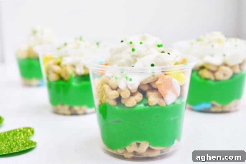 Layered St. Patrick's Day Pudding Parfaits with Lucky Charms cereal, green pudding, and whipped cream in clear cups, ready to enjoy.