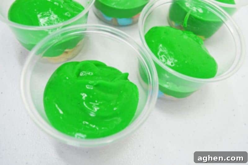 Step-by-step: Spooning the set green pudding over the first layer of Lucky Charms in a parfait cup.