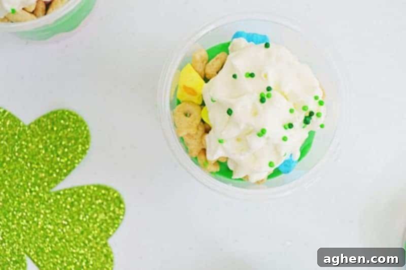Finished St. Patrick's Day Pudding Parfait cups topped with whipped cream and green sprinkles.