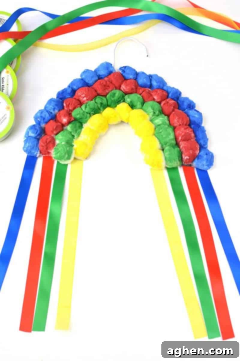 Colorful hanging cotton ball rainbow craft for kids, perfect for St. Patrick's Day or Spring.