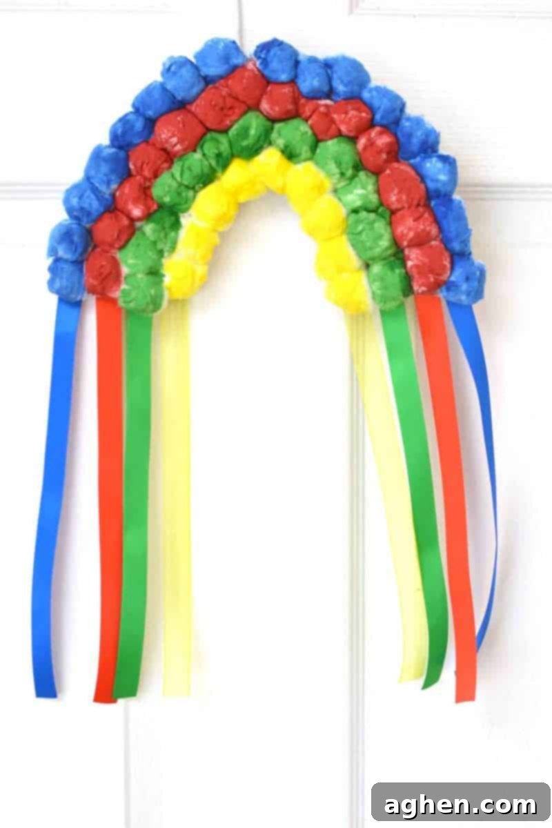 Gluing red, yellow, green, and blue ribbons to the back of the rainbow craft.