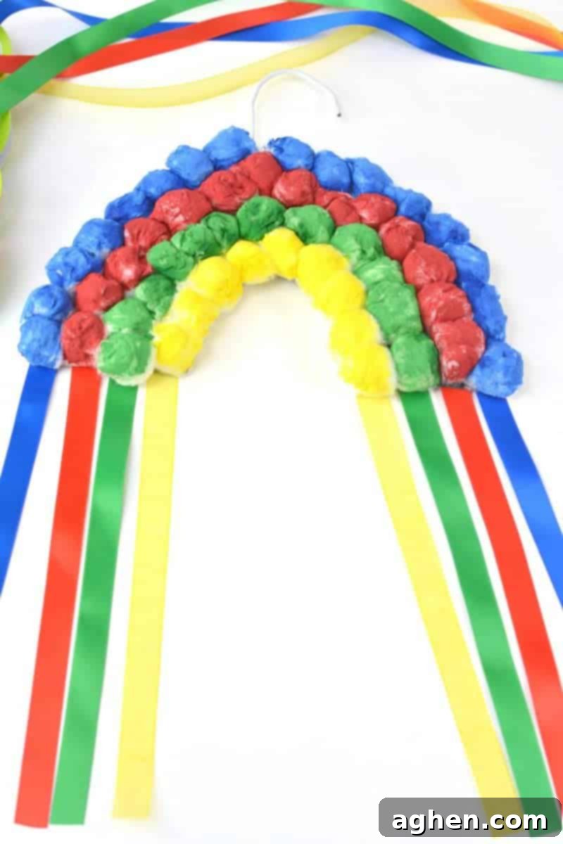 Finished hanging cotton ball rainbow craft with colorful ribbons.