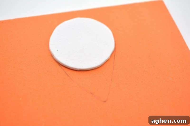 Step-by-step instruction: Cutting an orange beard shape from craft foam, designed to fit snugly around the leprechaun's white foam head for a St. Patrick's Day craft.