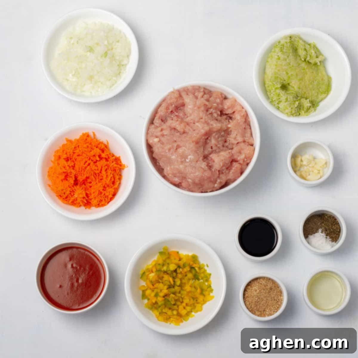 Easy Guilt-Free Turkey Meatloaf 3 Ingredients of ground turkey, breadcrumbs, onion, garlic, carrot, zucchini, egg, sauce, and spices in separate dishes.