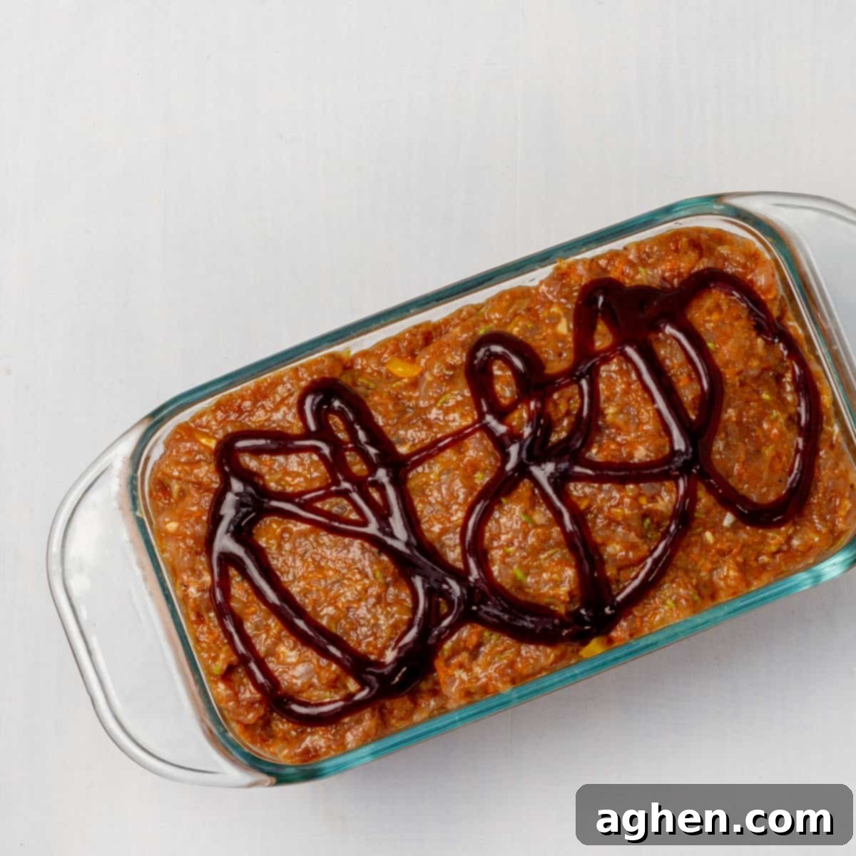 Easy Guilt-Free Turkey Meatloaf 6 Raw meat loat with tomato glaze in a baking dish.