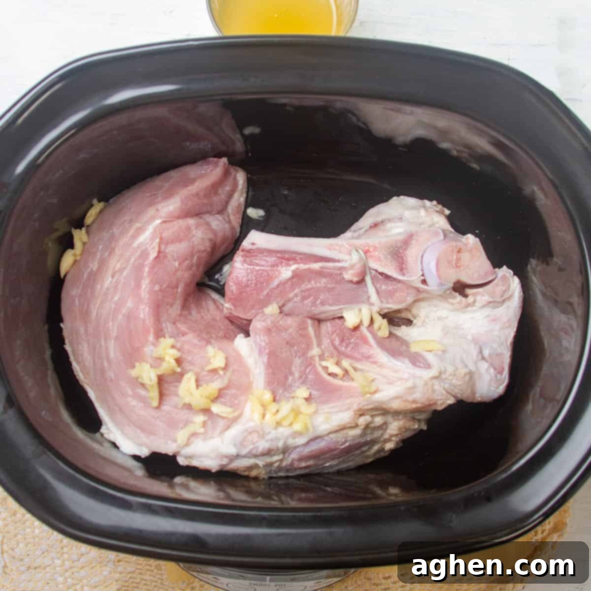 Add prepped pork shoulder and garlic to the slow cooker.