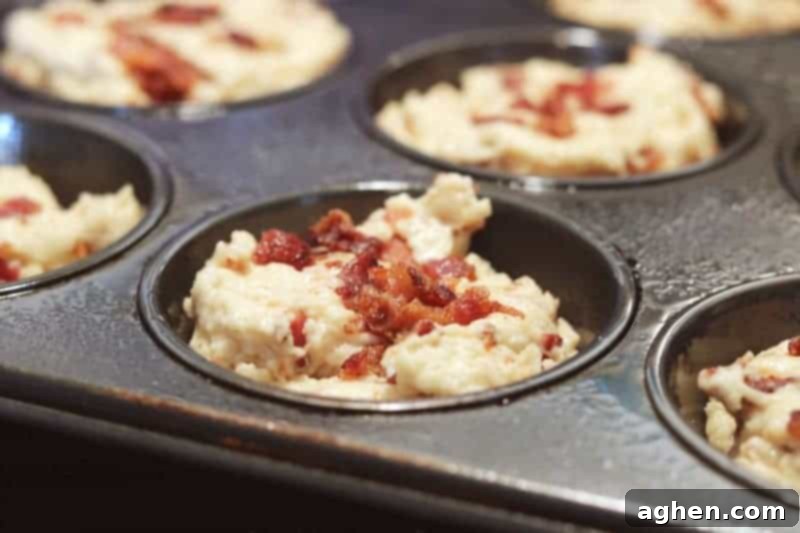 A close-up shot of a single Savory Maple Bacon Muffin, showcasing its fluffy texture and visible bits of Hatfield Applewood Smoked Bacon.
