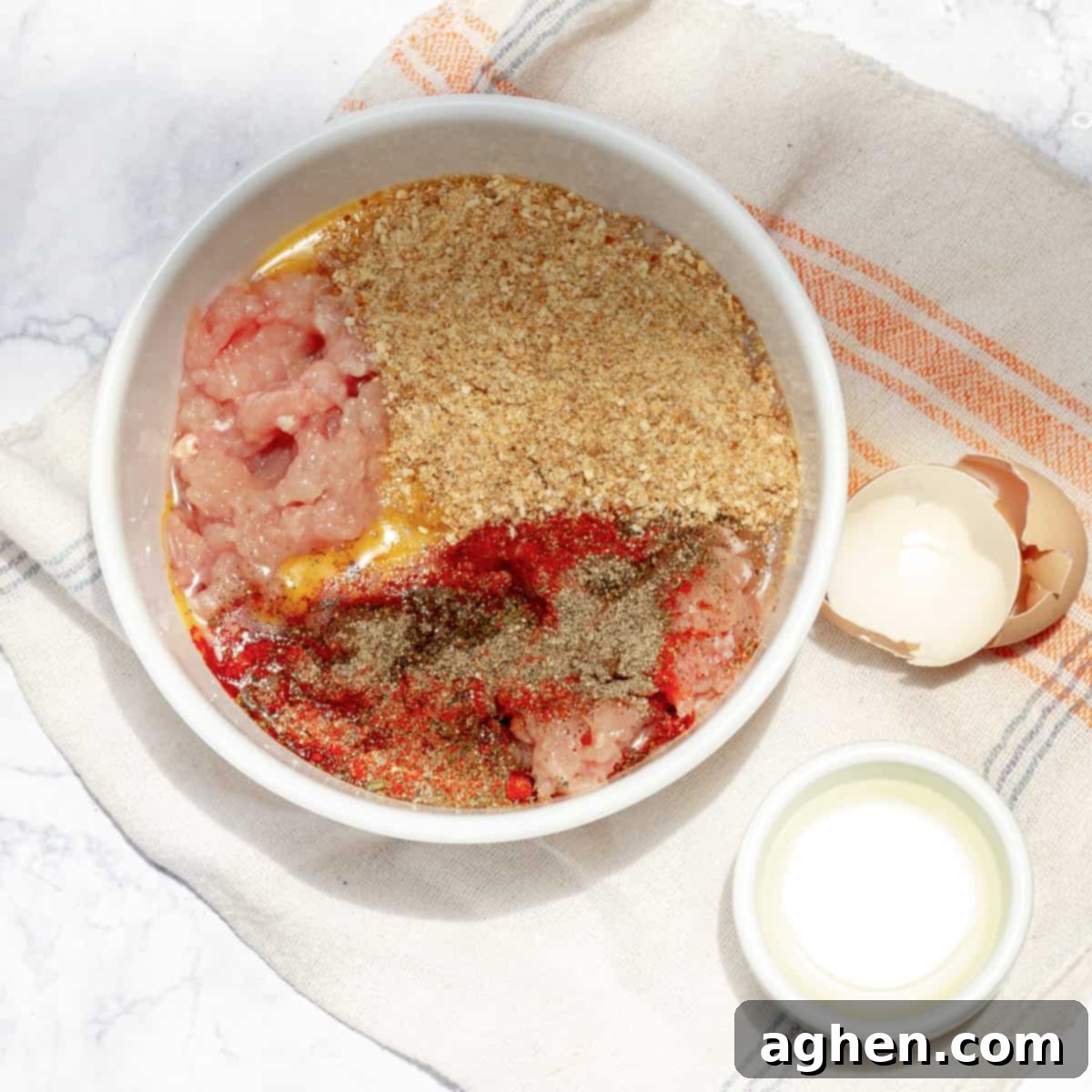 Raw chicken meat and seasonings combined in a bowl.