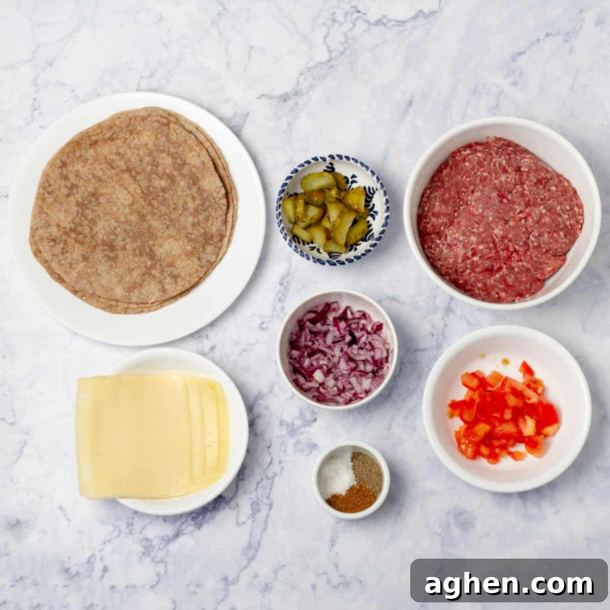 Smashed taco ingredients of tortillas, raw ground beef, peppers, onions, pickles, tomatoes, cheese, and seasonings in separate dishes.