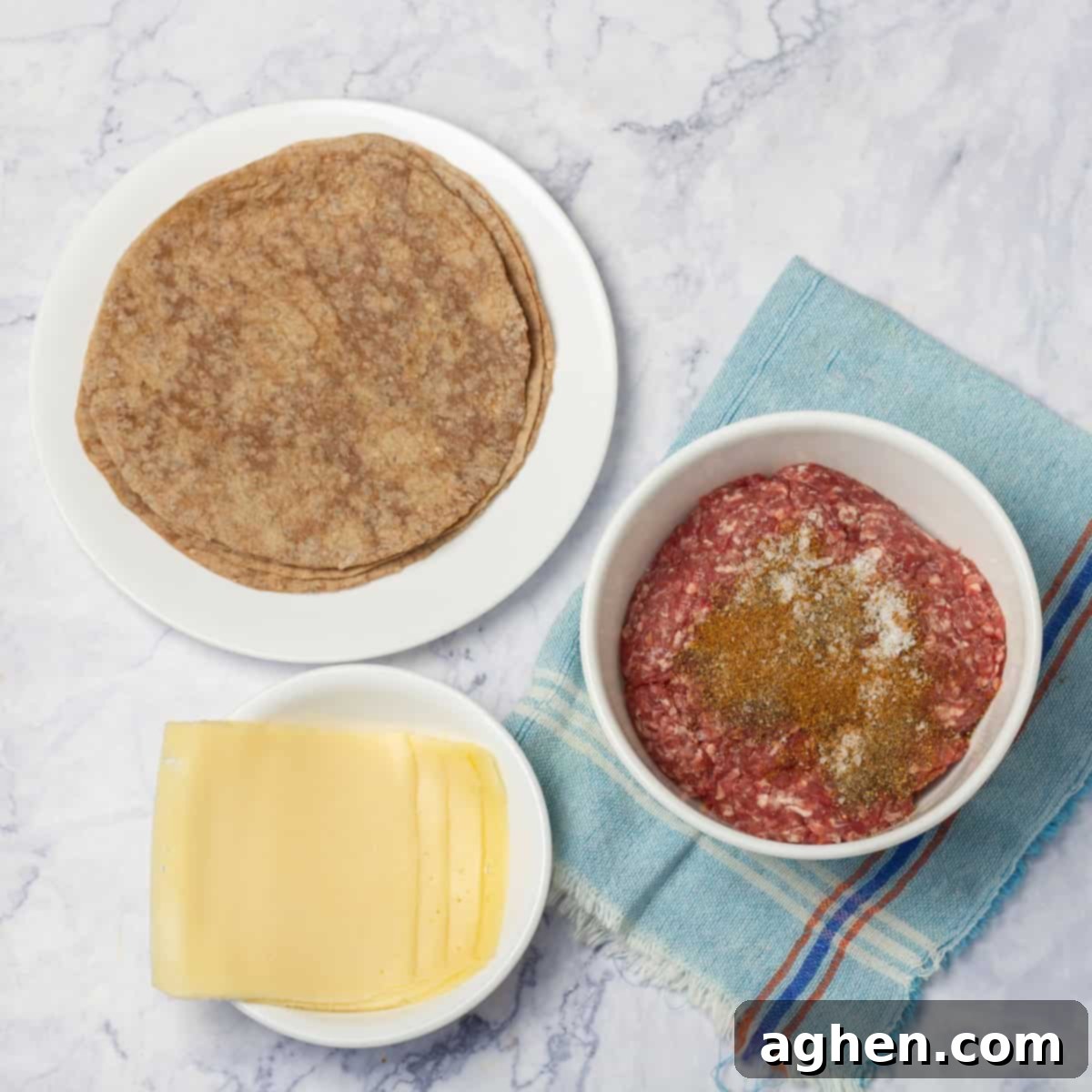 Ground beef marinating in seasonings with tortillas and cheese in separate dishes.