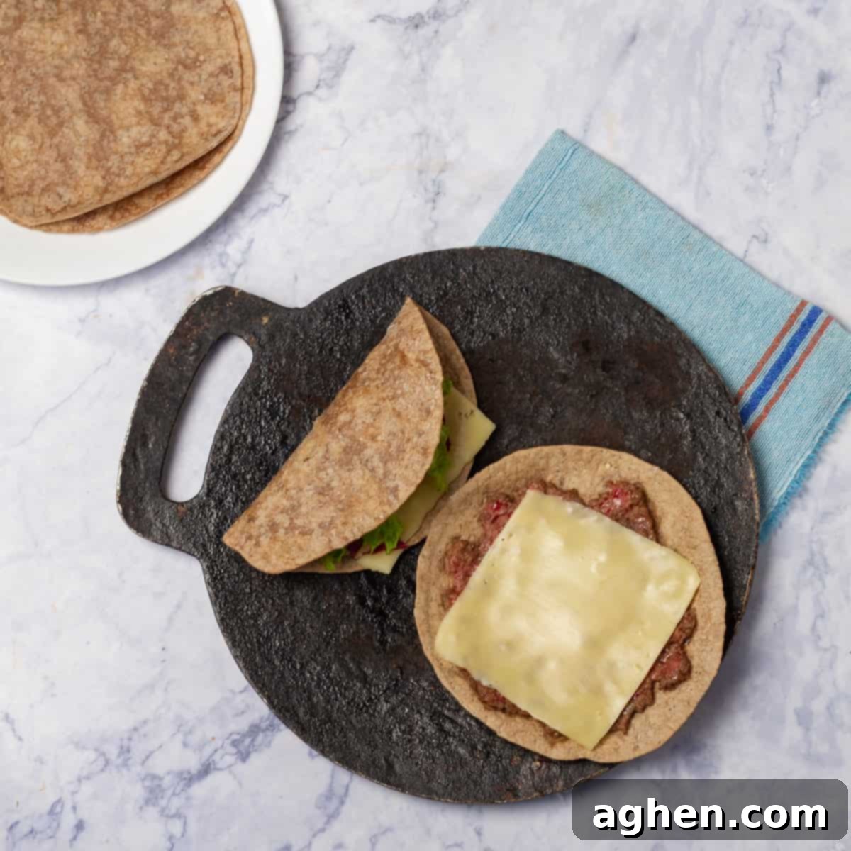 Smashed tacos covered with cheese cooking on a skillet.