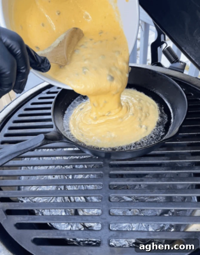 cornbread mix being pouring into cast iron on big green egg