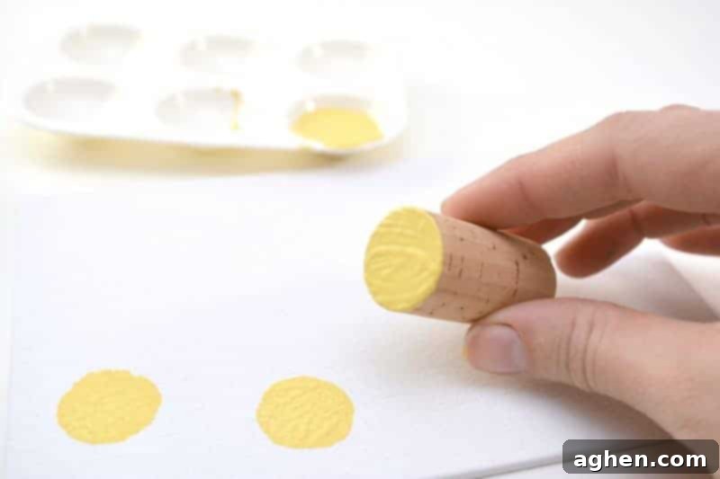 Step 1: Dipping a wine cork into yellow paint for the Easter chick craft.