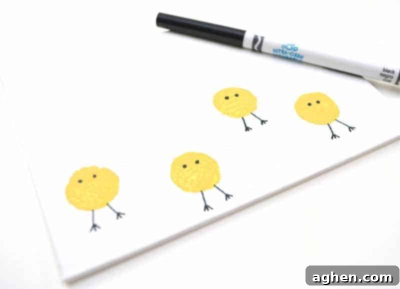 Step 4: Drawing eyes and legs on the dry yellow cork-stamped chick bodies with a black marker.