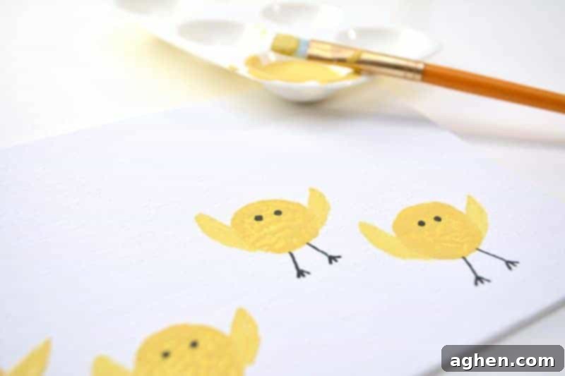 Step 5: Using a paintbrush to add small yellow wing shapes to each cork-stamped chick.