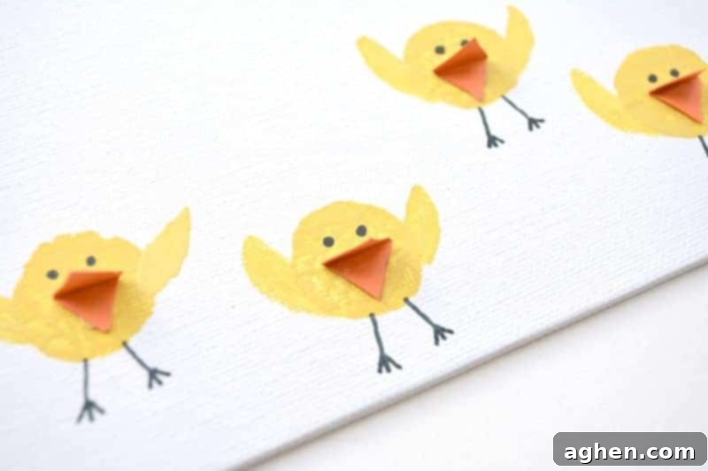 Step 6: Gluing orange paper beaks onto the face of each yellow cork-stamped chick.