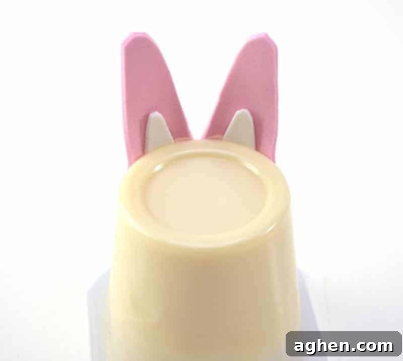 Step 5: Attach the assembled bunny ears to the top back of an upside-down vanilla pudding cup using glue.