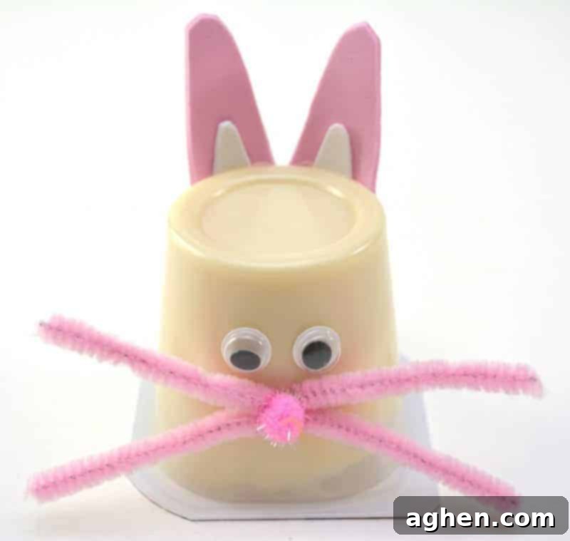 Step 10: Attach two pipe cleaner pieces to each side of the pom pom nose on the front of the pudding cup to create the bunny's whiskers.