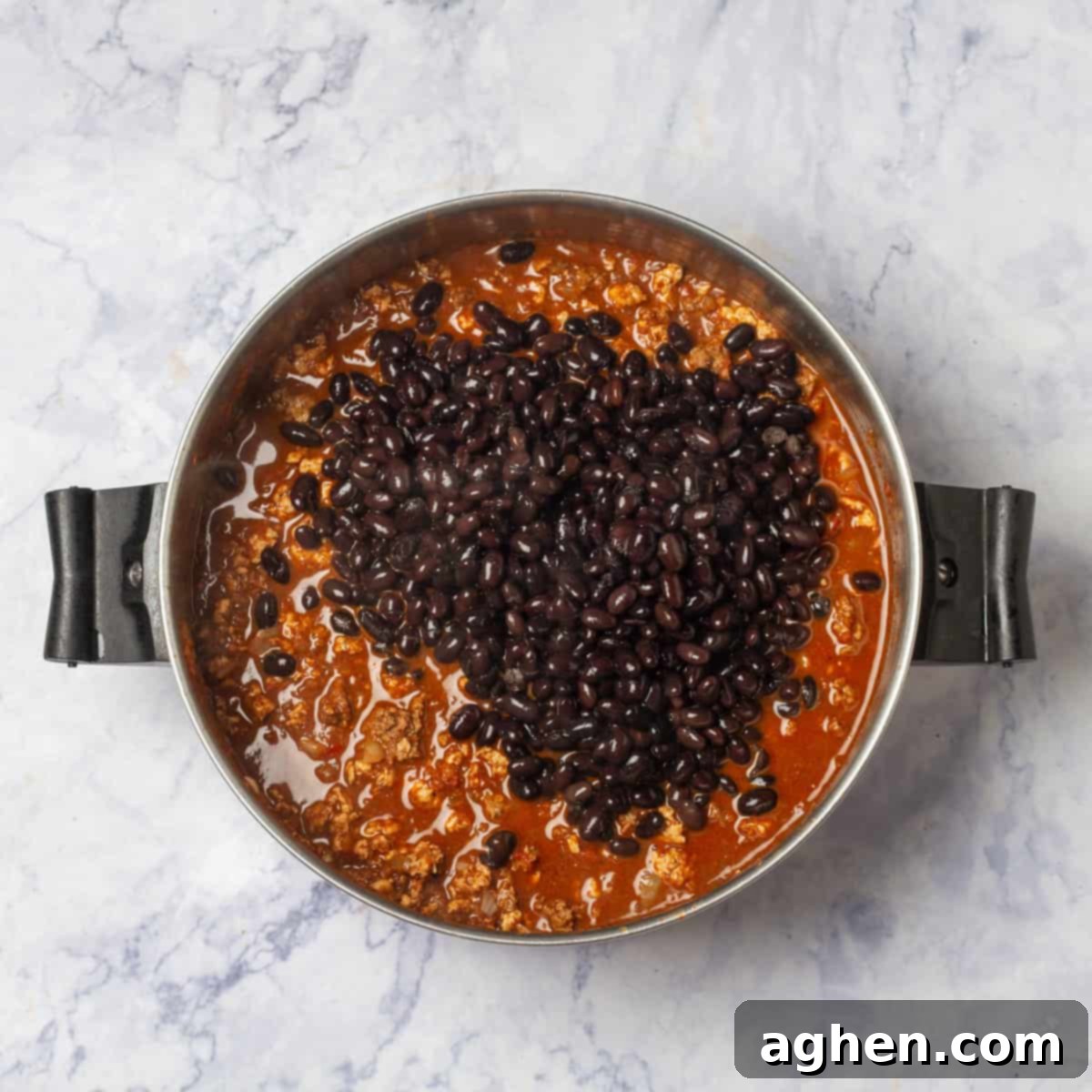 Irresistible Zero Point Turkey Chili 6 Black beans added into the simmering turkey, tomato, and onion mixture in a pot.