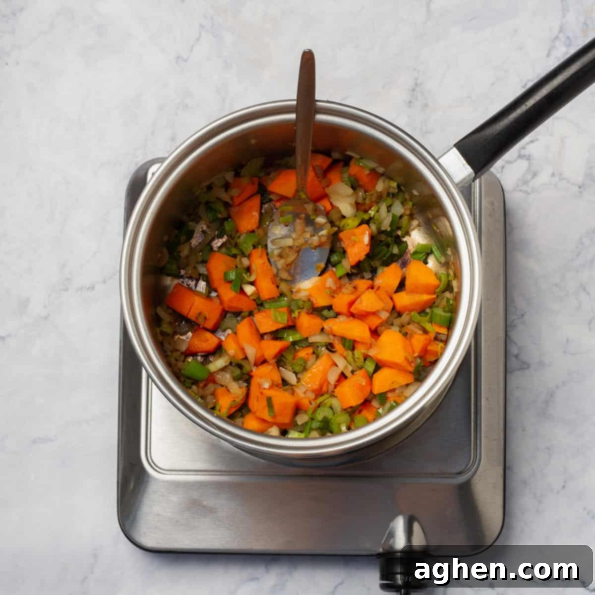 Carrots, celery, and onion sautéeing in a hot pot, releasing their sweet aromas.