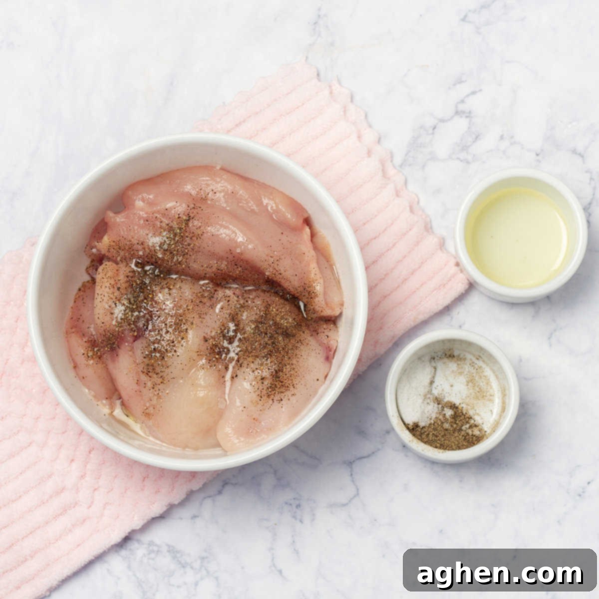 Seasoned raw chicken breasts in a dish before baking.