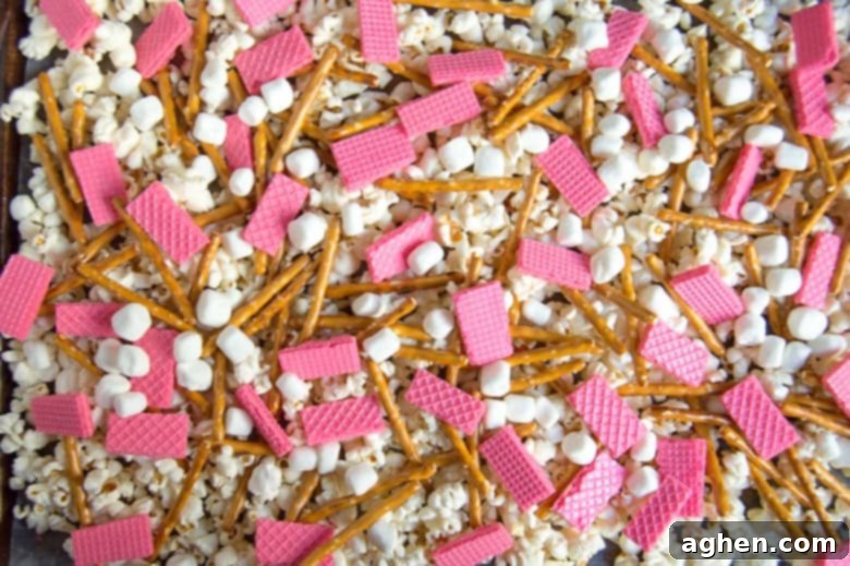 Popcorn, pretzels, strawberry wafers, and mini marshmallows spread on a baking sheet.