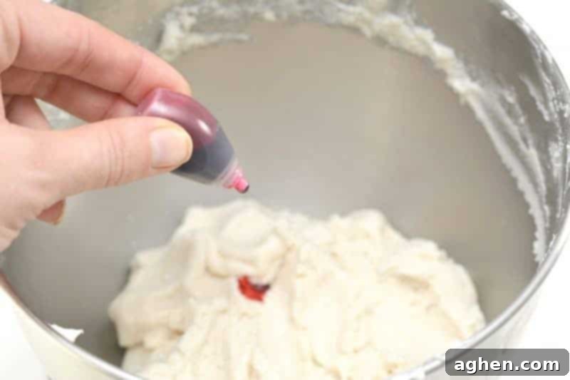 The playdough mixture in a bowl with drops of pink food coloring being added, ready to be mixed until uniformly colored. This step transforms the homemade no-cook playdough into vibrant pink princess playdough.