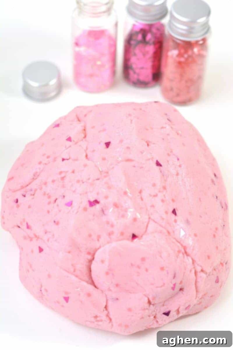 A finished ball of glittery pink princess playdough, smooth, vibrant, and sparkling, ready for creative play. This homemade no-cook playdough made with cake mix and icing is a perfect sensory activity for kids.