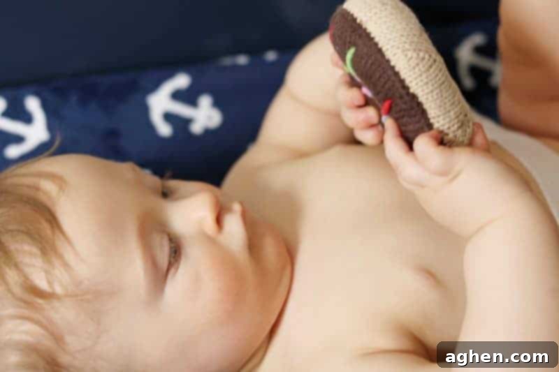 Happy baby playing with a donut rattle on the changing table during a diaper change