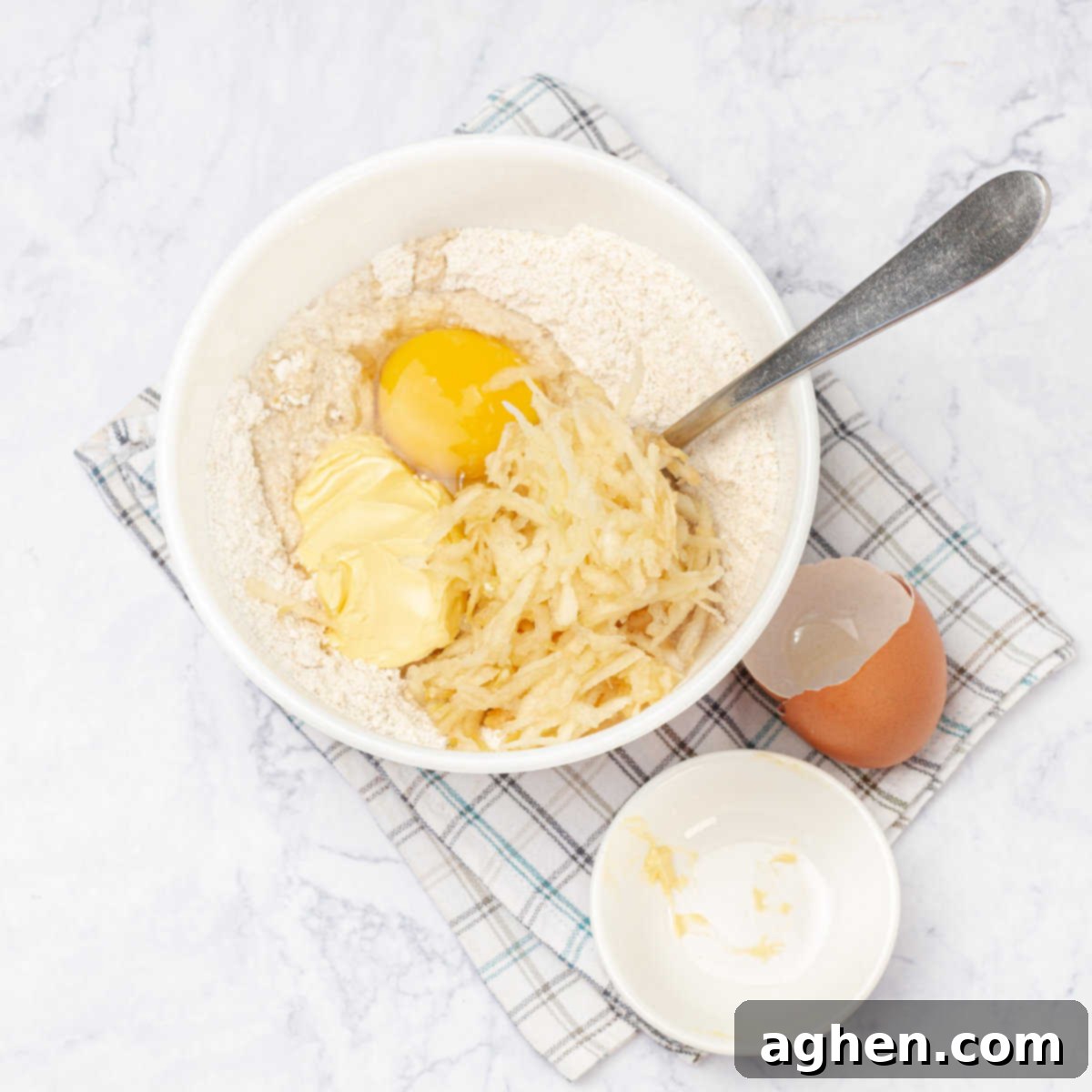 Mixing the wet ingredients for apple cider donut dough in a bowl, showing grated apples, egg, and liquids combined.