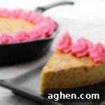 A cast iron skillet cookie recipe for a gigantic sugar cookie with rainbow sprinkles and homemade pink frosting. The sprinkles give the skillet cookie a funfetti vibe, making it perfect for birthday parties or other celebrations.