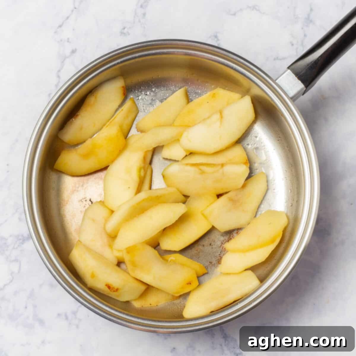 Sautéing the apples in a hot pan, showing the beginning of the caramelization process.