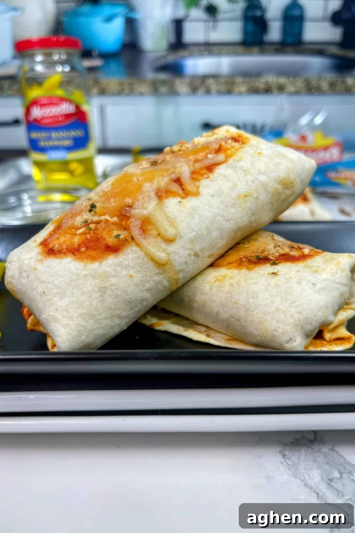 Snack Goals: Baked Pizza Burritos 2 Two golden brown pepperoni pizza burritos, sliced diagonally and ready to serve on a plate.