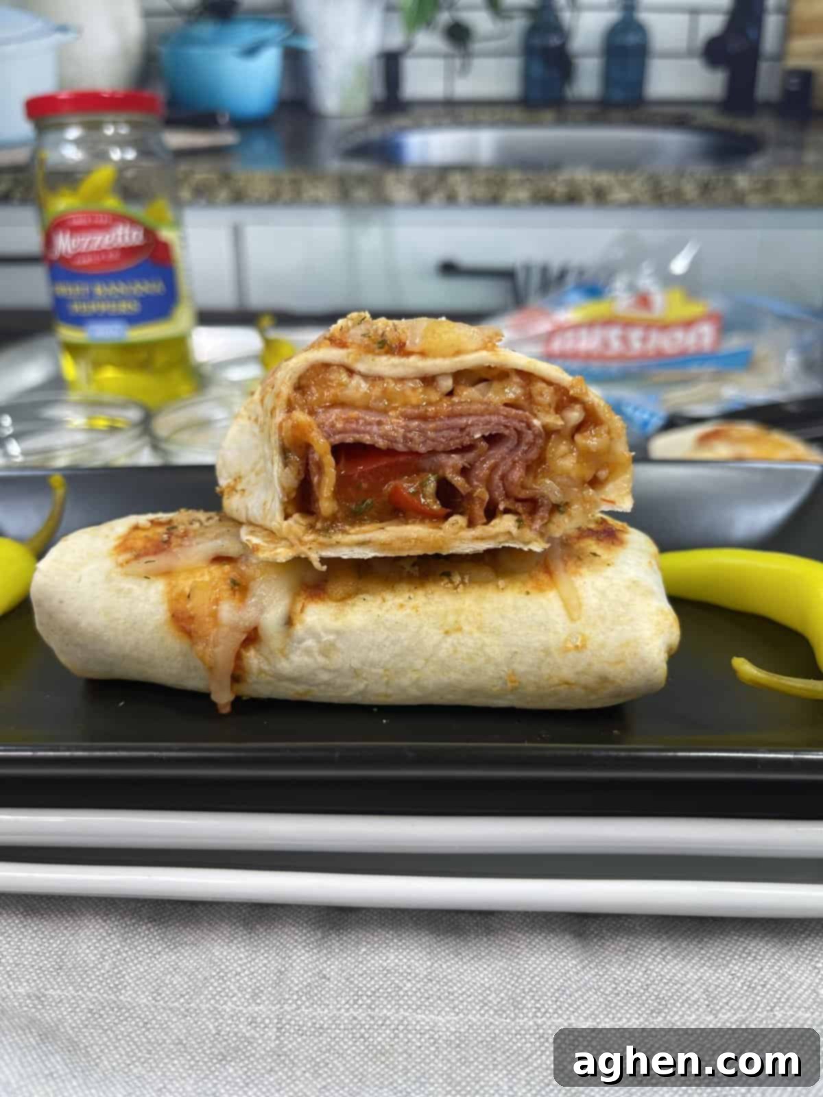 Snack Goals: Baked Pizza Burritos 5 A freshly baked pizza burrito, cut in half diagonally, revealing its delicious pepperoni, cheese, and sauce filling.