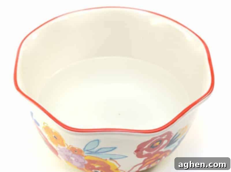 Hot water being poured into a large mixing bowl, ready for the fabric softener ingredients.